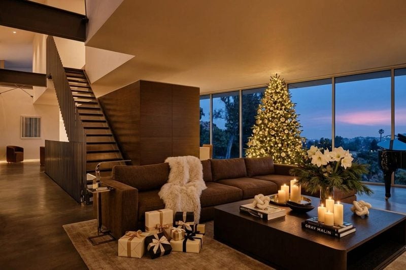 A lit Christmas tree beside the grand piano in a living room with floor-to-ceiling windows at dusk