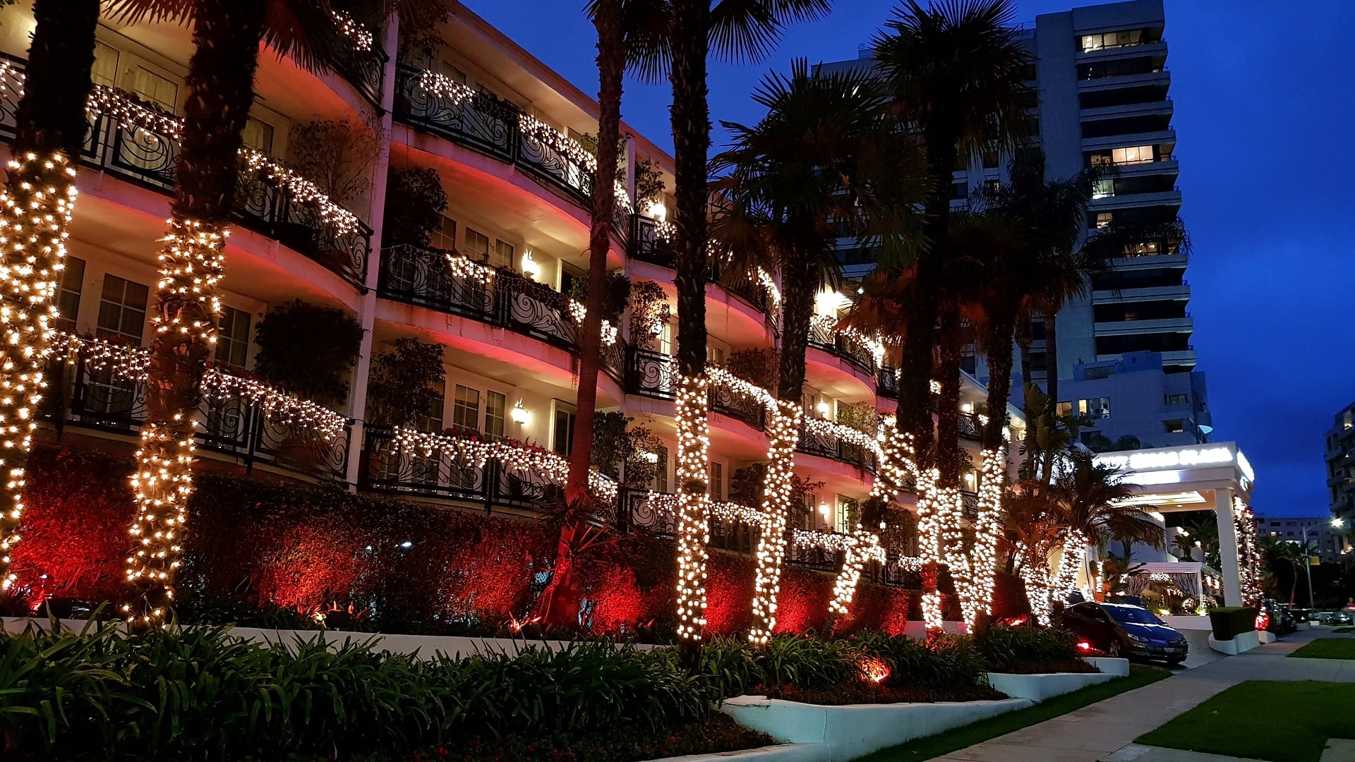 The Beverly Hills Hotel strung with holiday lights along its pink facade at dusk