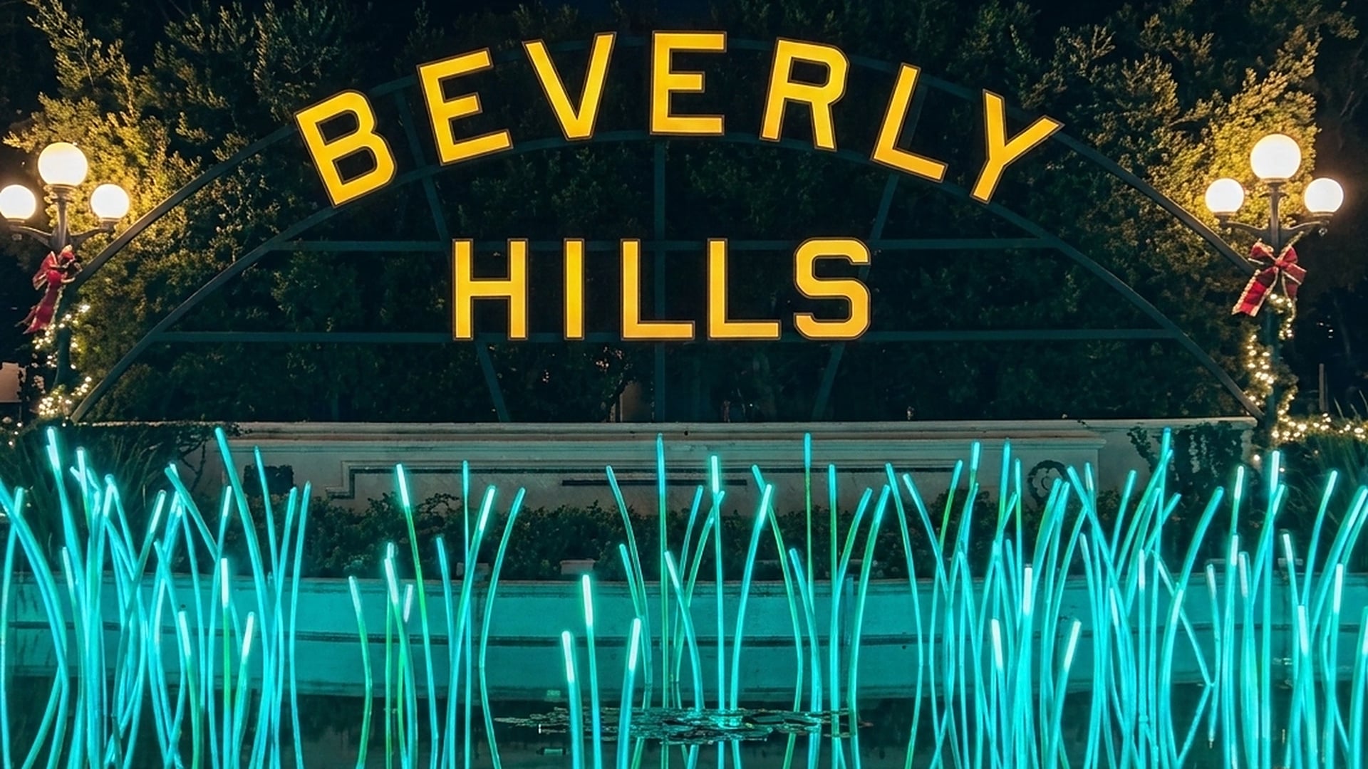 The Beverly Hills sign at the Lily Pond in Beverly Gardens Park glowing with holiday lights at night