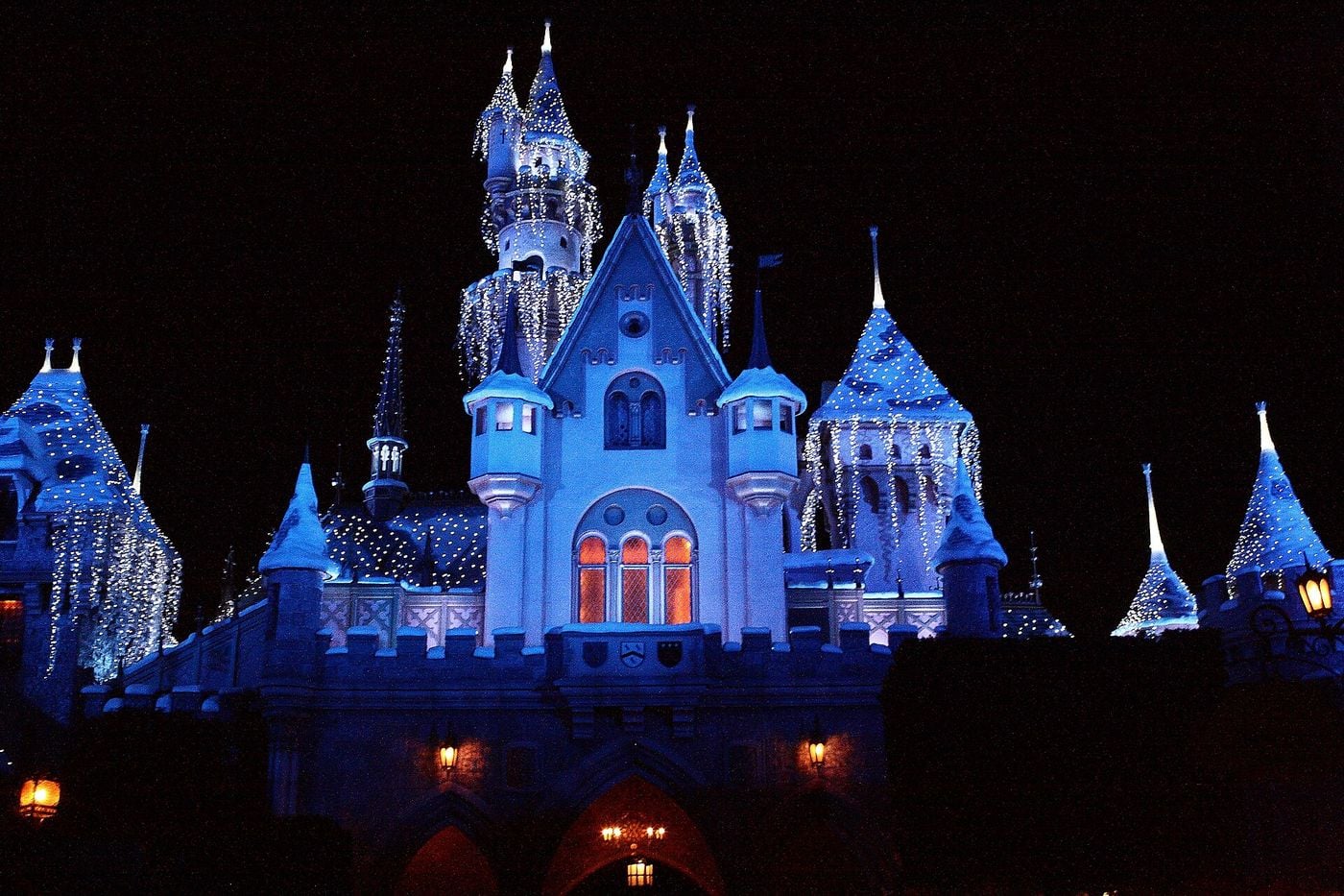 Sleeping Beauty Castle at Disneyland covered in icicle lights for the holidays at night