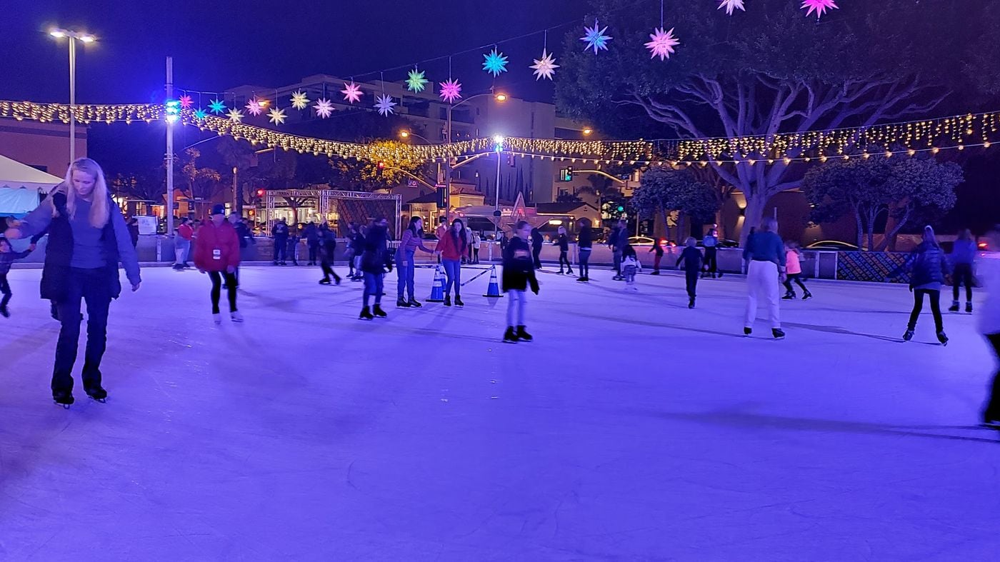 Skaters at night under string lights and glowing stars at Ice at Santa Monica