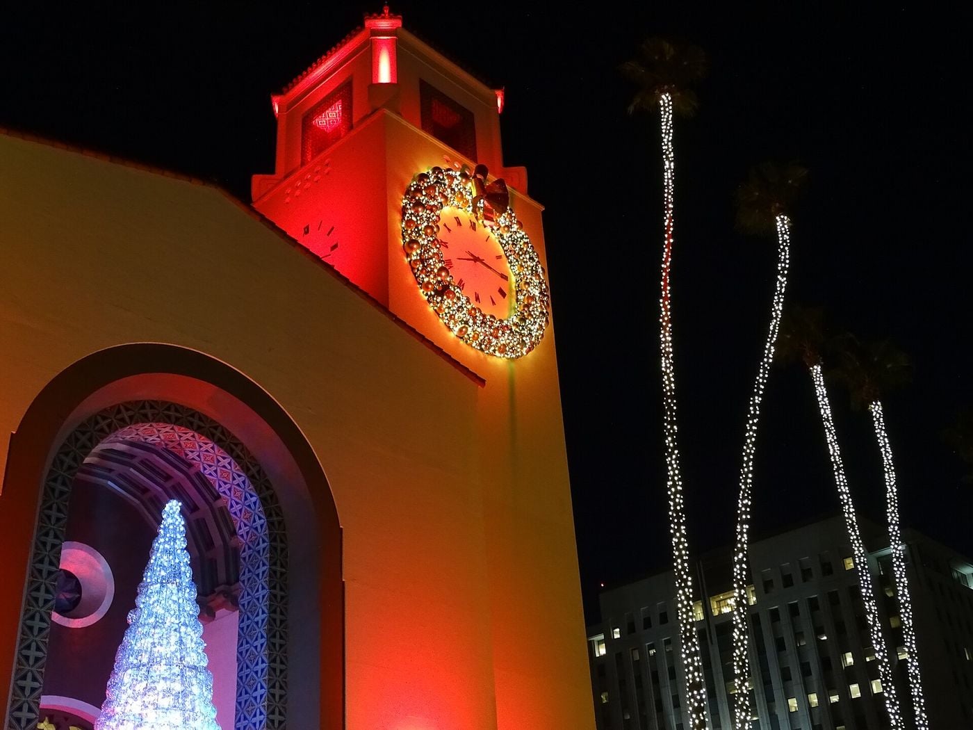 Union Station's clock tower lit red with a Christmas wreath and a white holiday tree in the entrance arch