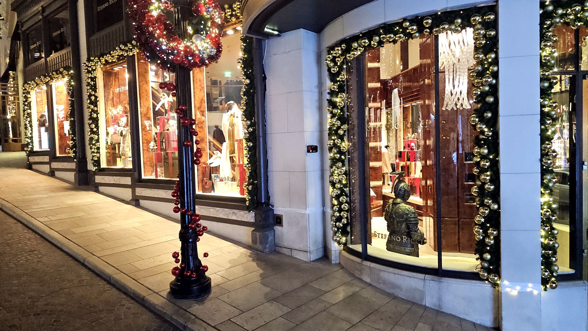 Shop windows framed in Christmas garlands and a ribbon-wrapped lamp post on Two Rodeo in Beverly Hills
